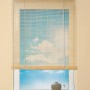 Naturfarbenes OBI Bambus-Raffrollo, 140x160 cm, am Fenster mit Blick auf blauen Himmel.