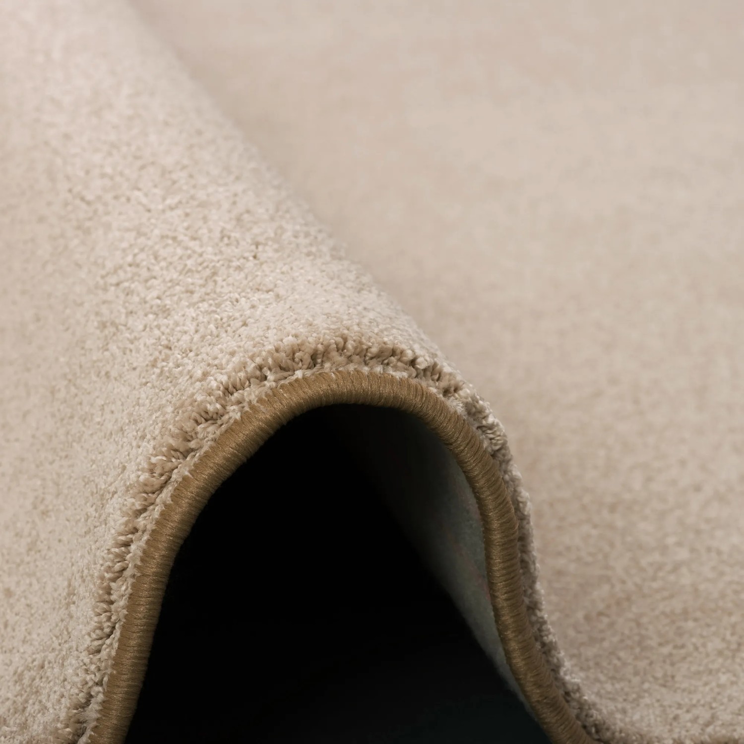 Detailaufnahme: Gerollter, beiger Snapstyle Hochflor Teppich 100x300 cm. Weicher Luxus Velours Teppich.