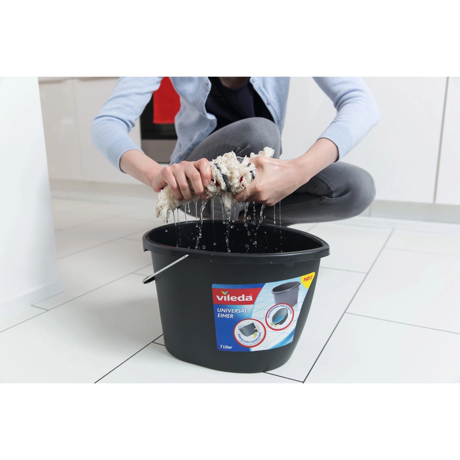 Vileda Wischmat-Combi Flachwischer wird über einem schwarzen Eimer ausgewrungen.