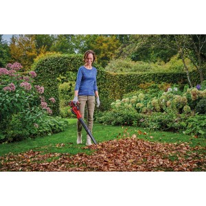 Frau benutzt Einhell Akku-Laubbläser GE-UB 18/250 Li E im Garten, um Laub zu entfernen.