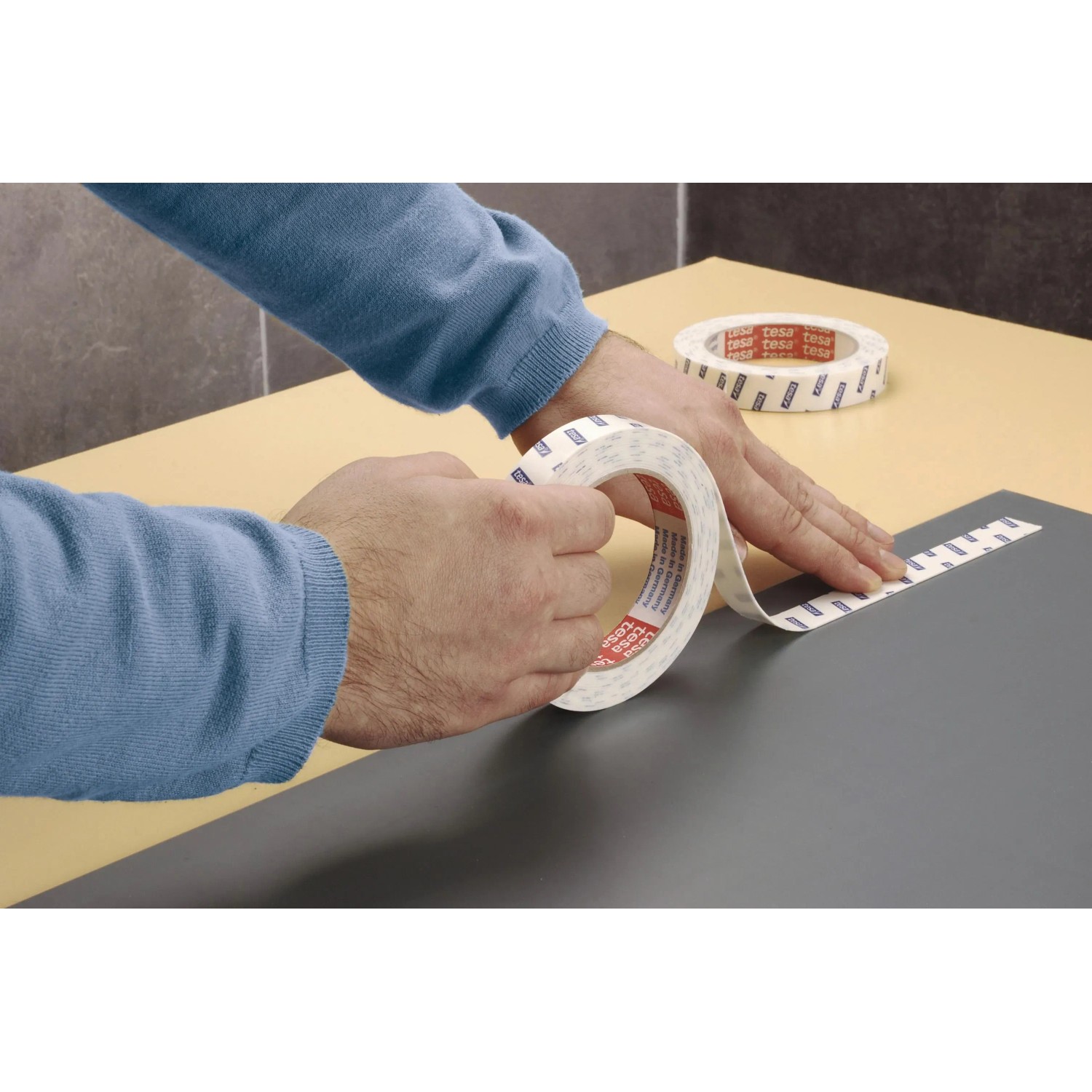 Anwendung von Tesa Powerbond Montageband Mirror, 5m x 19mm, auf einer grauen Fläche.