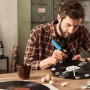 Mann klebt mit blauem Bosch Gluey Heißklebestift Deko auf Schallplatte. Heißklebegerät für Bastelprojekte.