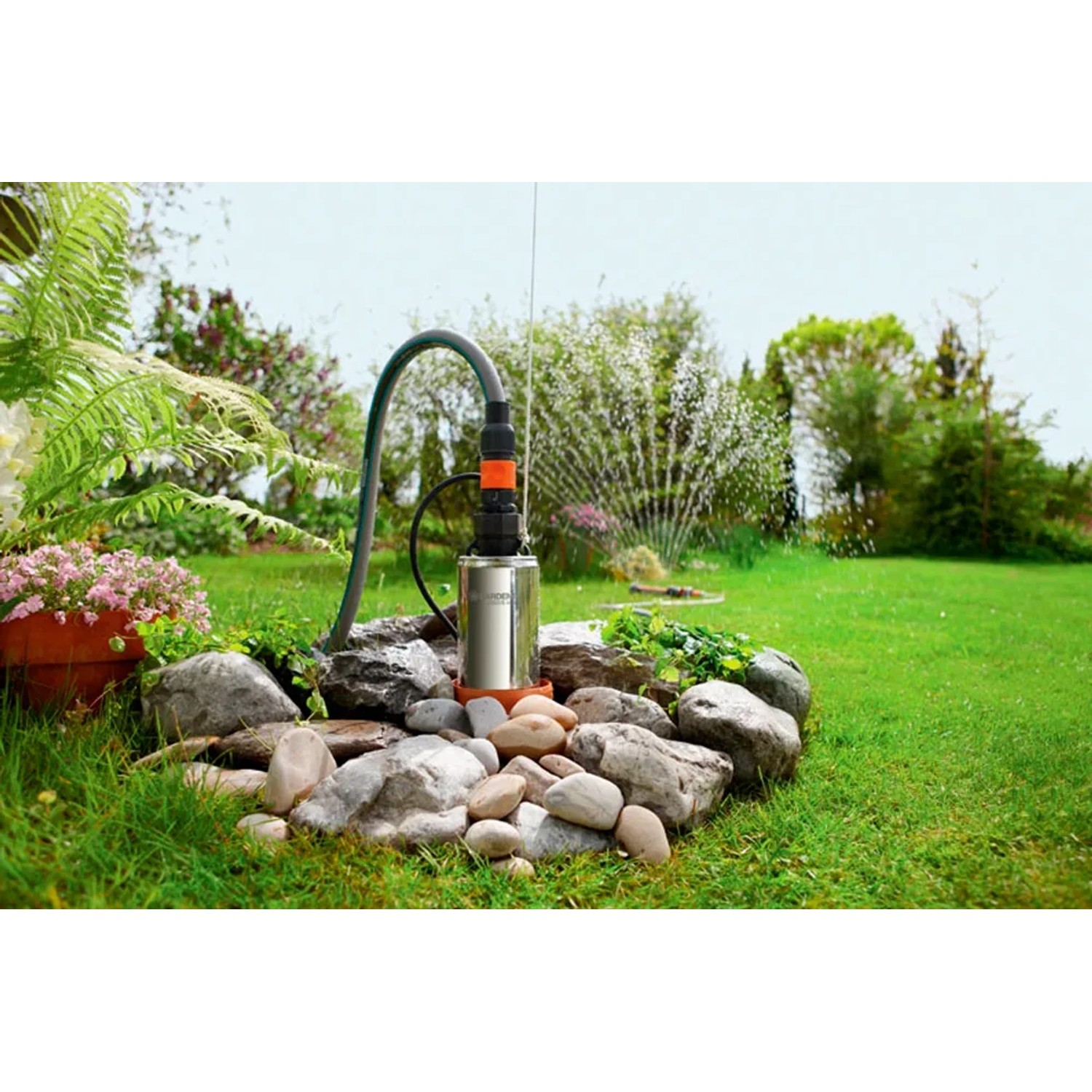 Gardena Tiefbrunnenpumpe 6000/5 inox im Garten, umrandet von Steinen. Elektro-Pumpe mit Schlauch.