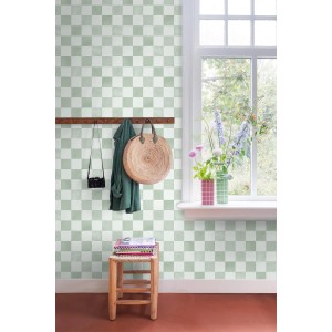 Grüne Vliestapete mit Karomuster an einer Wand, dekoriert mit Garderobe und Blumen am Fenster.