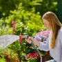 Frau bewässert Blumen mit Gardena Bewässerungsbrause AquaCount im Garten.