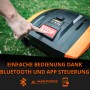 Hand drückt roten STOP-Knopf auf Yard Force Mähroboter. Einfache Bluetooth App-Steuerung für Rasenpflege.