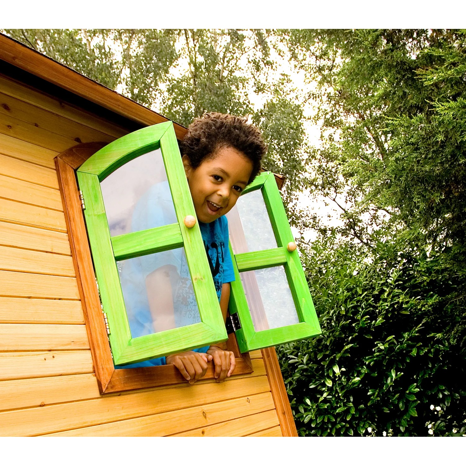 Kind im Fenster des braun-grünen Axi Sarah Spielhauses mit grüner Rutsche.