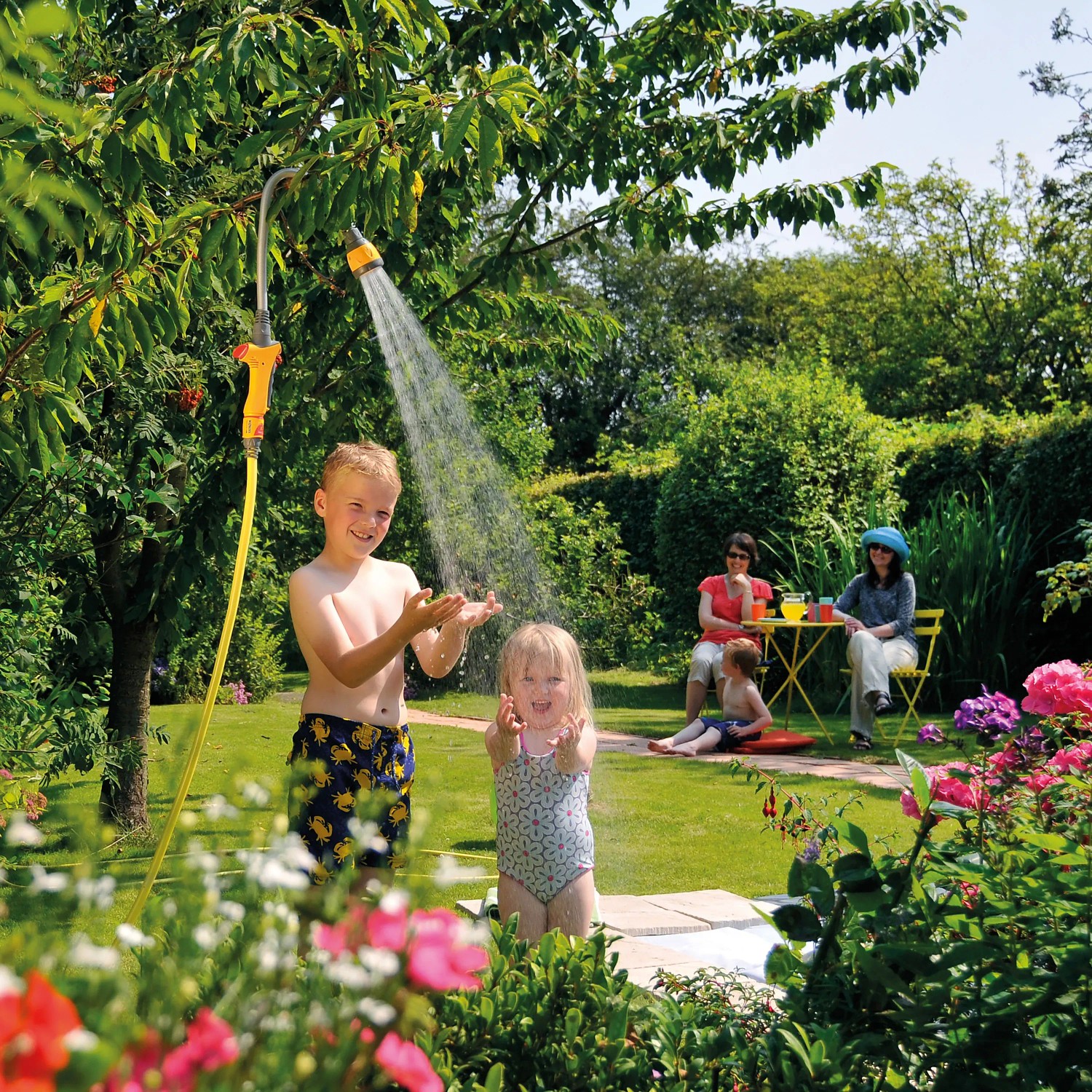 Hozelock Flexi Spray Gartenbrause als Gartendusche im Einsatz mit spielenden Kindern.