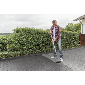 Mann trägt Ultrament Betonlasur Pflaster Frisch Anthrazit mit Farbroller auf Pflastersteine auf.