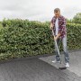Mann trägt Ultrament Betonlasur Pflaster Frisch Anthrazit mit Farbroller auf Pflastersteine auf.