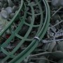 Detailansicht des grünen Kunststoffrahmens eines künstlichen Weihnachtskranzes mit Blättern und roten Beeren.