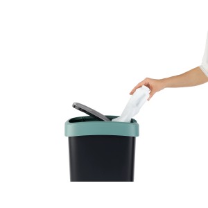 Rotho Swingeimer Twist 10 l Mistletoe Green: Hand wirft Müll in schwarzen Mülleimer mit grünem Deckel.