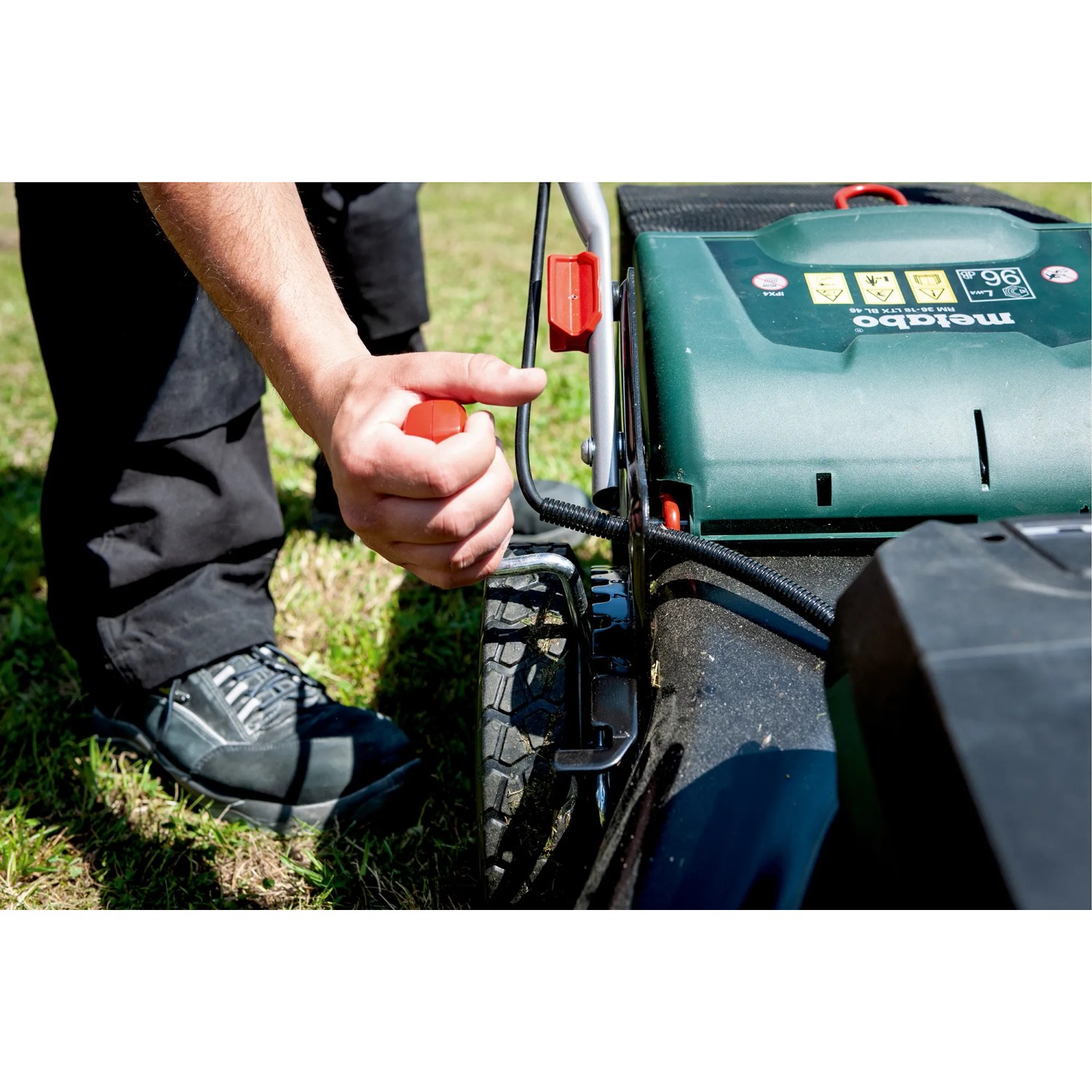 metabo Akku-Rasenmäher RM 36-18: Hand bedient roten Griff am Rasenmäher.