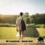 Mann trägt Falthocker in Tragetasche auf Schulter auf Wiese vor Zelt. Perfekt für Camping, Angeln & Outdoor-Abenteuer.