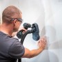 Wolfcraft Absaugsystem HSD 68/100 im Einsatz mit Bohrmaschine an Wand.