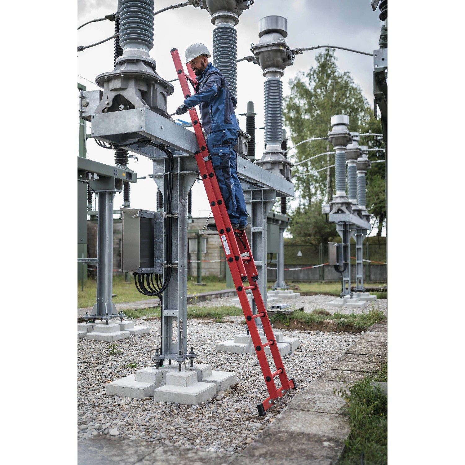 PROREGAL Sprossen-Schiebeleiter, 2-teilig, GFK, mit Traverse, 2x8 Sprossen. Mann arbeitet an Strommast.