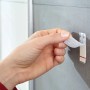 Anbringen eines Tesa Powerstrips Haken Waterproof (Edelstahl, Large) an einer grauen Wand.
