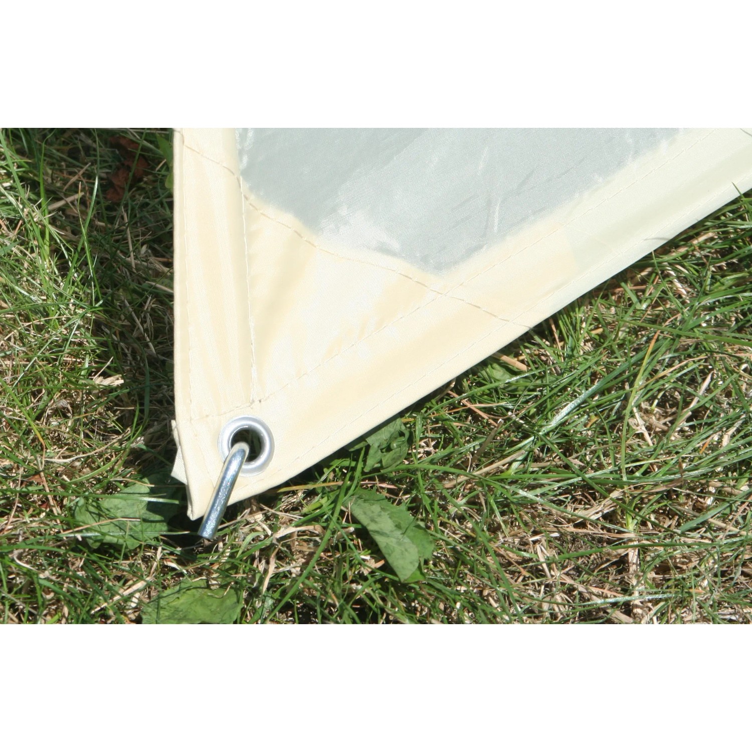 Detailaufnahme: Sandfarbenes Floracord Camping Sonnensegel Viereck, Ecke mit Öse und Hering im Gras.