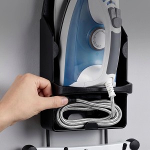 Schwarzer Relaxdays Bügeleisenhalter aus ABS-Kunststoff und Stahl an der Wand. Bügeleisen eingesetzt, Hand verstaut Kabel im Fach. Platzsparend.