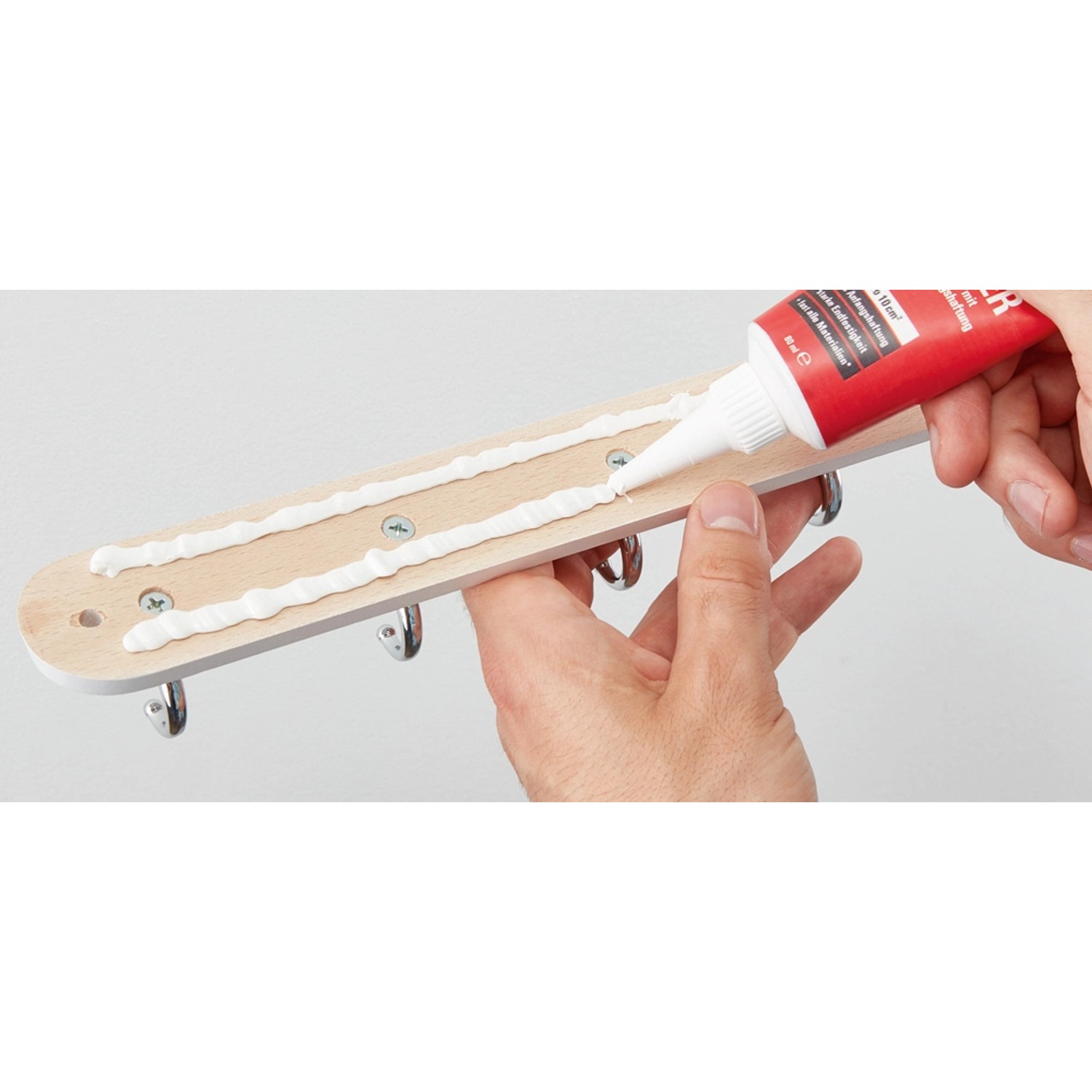 Anwendung von Fischer 320 Kilo Kleber auf einer Garderobe. Der Kleber ist lösemittelfrei und überstreichbar.