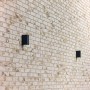 Wand mit Elabrick Verblender Sevilla, 24x7,1 cm, in hellem Beige und Braun mit zwei schwarzen Lampen.