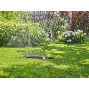 Gardena Viereckregner AquaZoom L bewässert Rasenfläche im Garten.