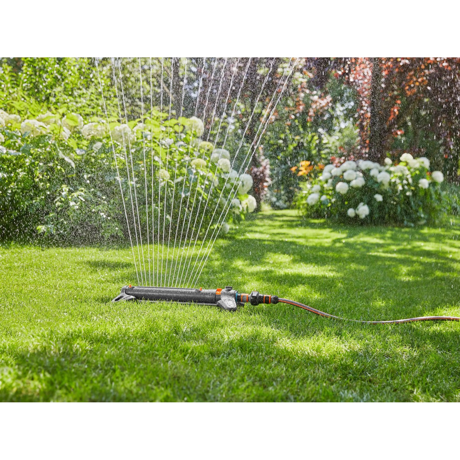 Gardena Viereckregner AquaZoom L bewässert Rasenfläche im Garten.