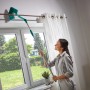 Frau reinigt Gardinenstange mit Leifheit Wand- und Deckenbesen Dusty mit Teleskopstiel.