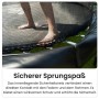 Detailaufnahme: Schwarzes Zero Gravity Gartentrampolin mit Sicherheitsnetz und Füßen auf der Sprungfläche.