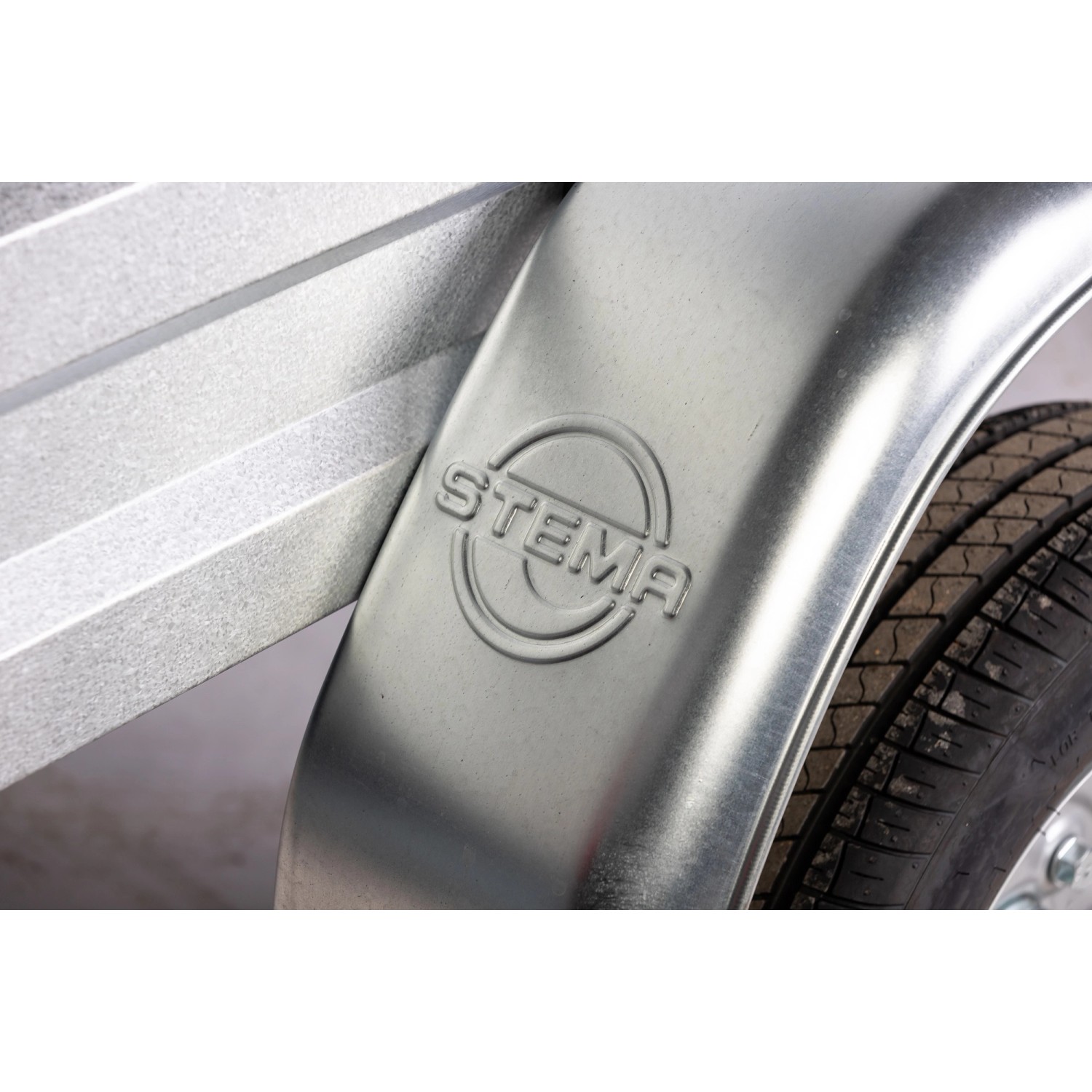 Detailansicht Stema Anhänger Variolux 850: Radkasten mit Stema Logo und Reifen.