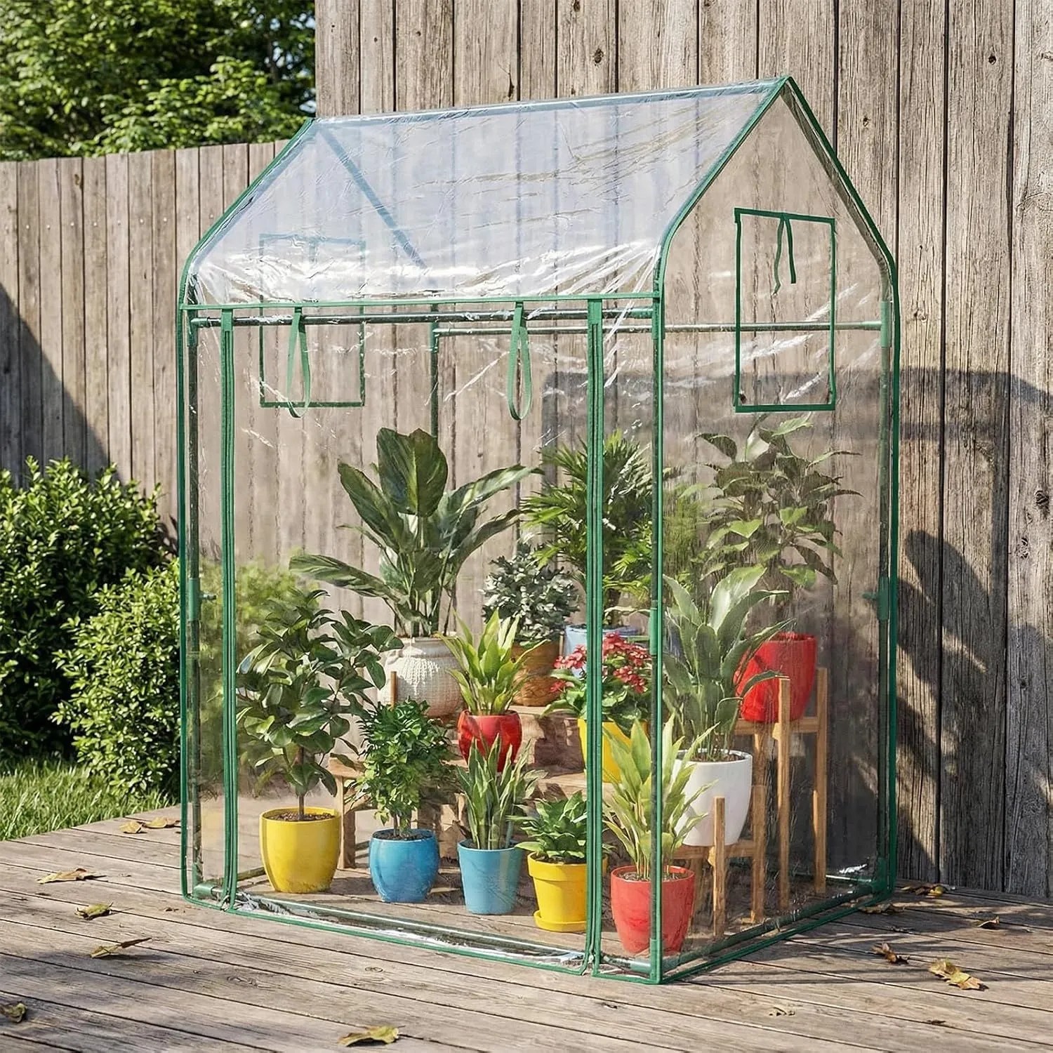 Costway Tomatengewächshaus (129x80x173cm) mit Sonnenschutznetz und Tür, gefüllt mit Pflanzen.