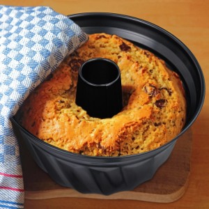 Schwarze Gugelhupfform aus Carbonstahl mit Antihaft, gefüllt mit gebackenem Kuchen. Ideal für Napfkuchen.