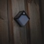 Schwarze Solar-Wandleuchte Pretoria mit Sensor an Holzwand. Außenleuchte mit Bewegungsmelder.