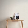 Strukturierte, matte, graue Vliestapete Uni von FSC® an Wand hinter Holztisch.