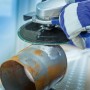 Winkelschleifer mit LUX Fiberscheibe Classic beim Entrosten eines Metallrohrs.