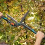 Gardena EnergyCut 2in1 Hand-Heckenschere beim Heckenschnitt. Schwarz-türkis mit orangenem Knopf.