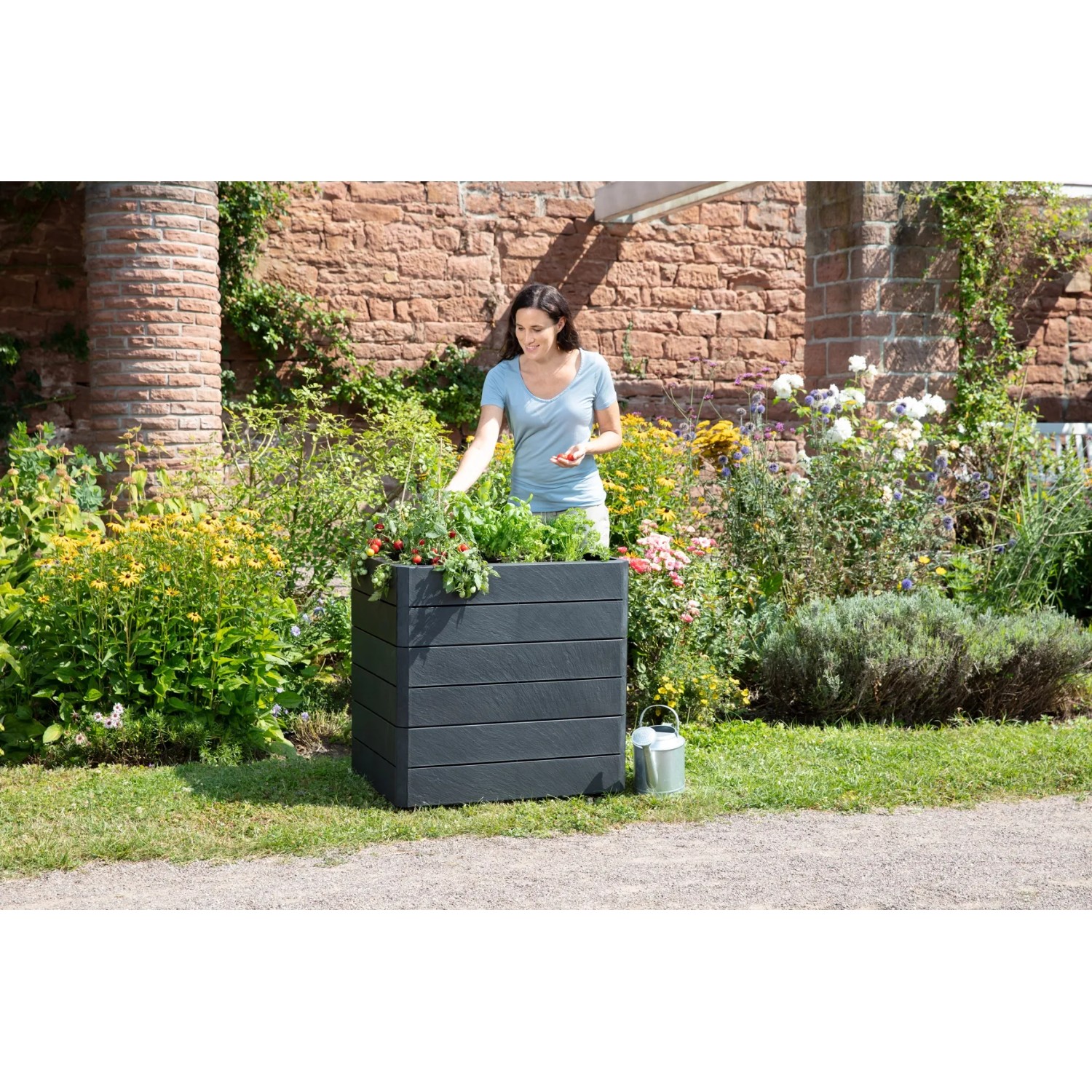Garantia Hochbeet Ergo Quadro M 75 Stone im Garten mit Frau. Kunststoff-Hochbeet in Steinoptik.