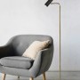 Moderne Trio LED-Stehleuchte Marley in Messing matt neben Sessel.