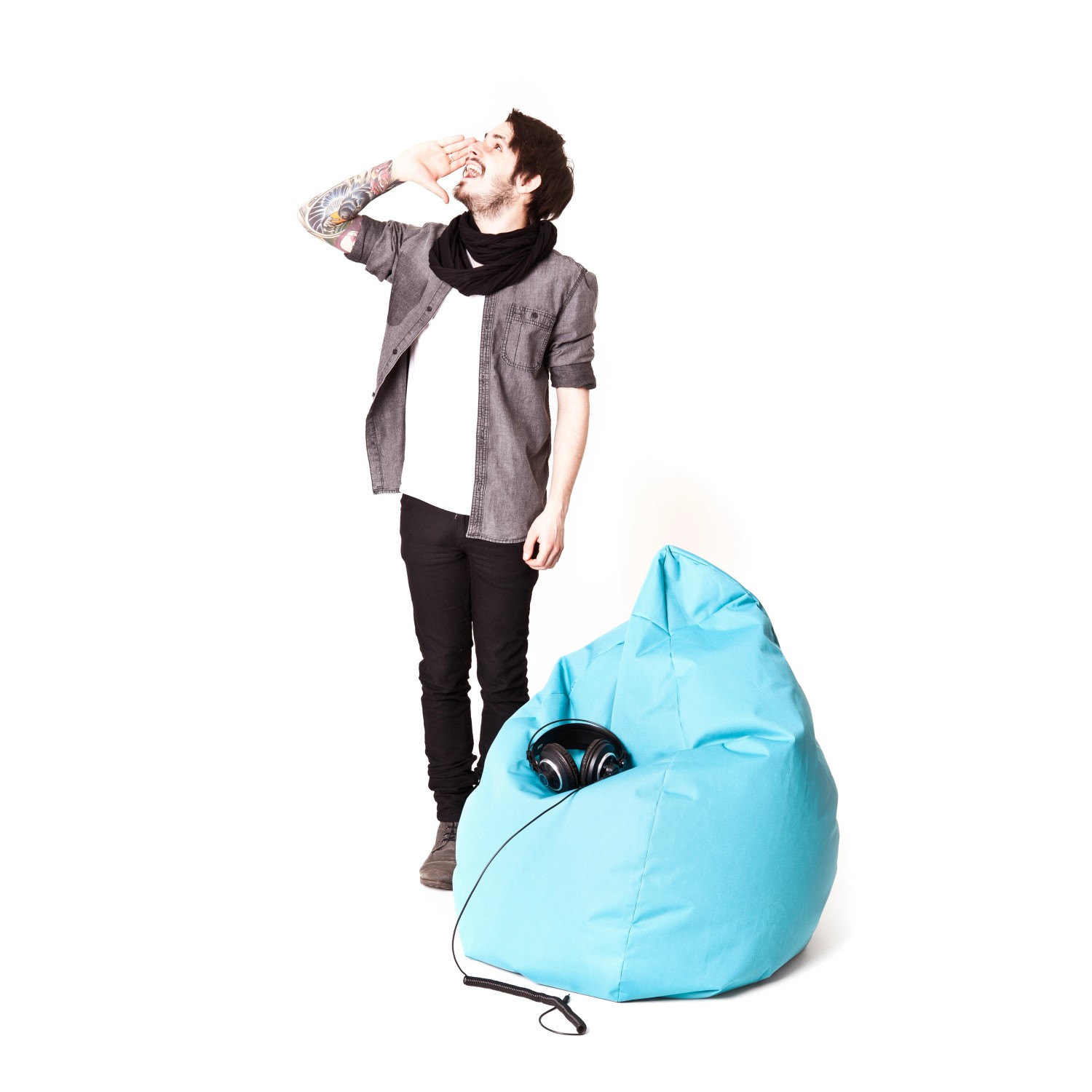 Blauer Sitting Point Sitzsack Brava (120 l) mit Kopfhörern, daneben eine Person.