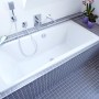 Eingebaute Badewanne in Weiß mit grauen Fliesen und Armaturen im Badezimmer.