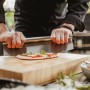 Edelstahl Pizzaschneider von Enders beim Pizzaschneiden auf Holzbrett, Grillutensil.