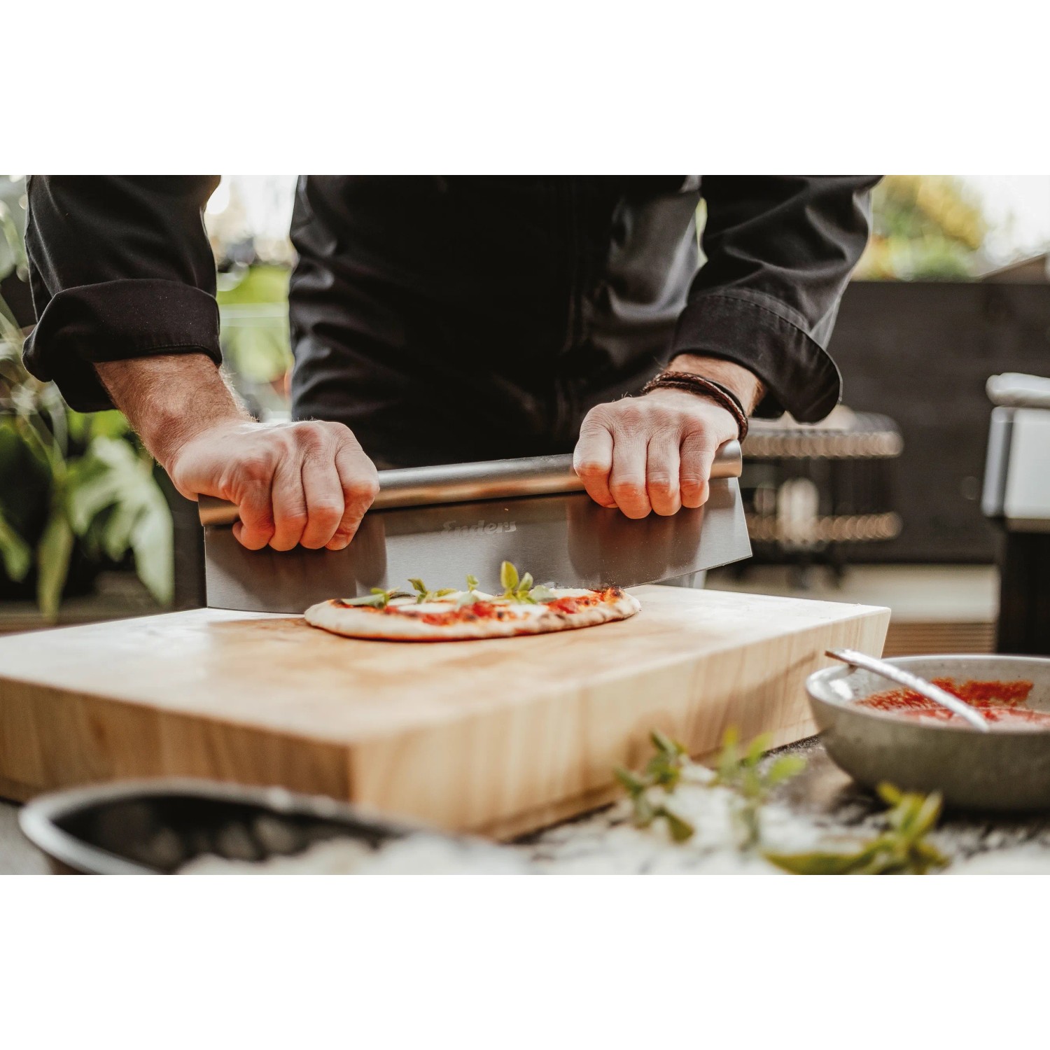 Edelstahl Pizzaschneider von Enders beim Pizzaschneiden auf Holzbrett, Grillutensil.