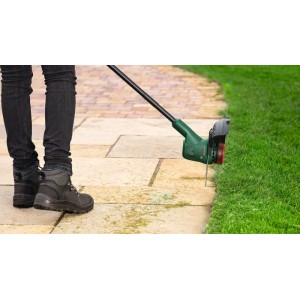 Bosch Akku-Rasentrimmer EasyGrassCut trimmt Rasenkanten. Grüne Maschine schneidet Gras präzise an gepflastertem Weg. Einfache Handhabung.