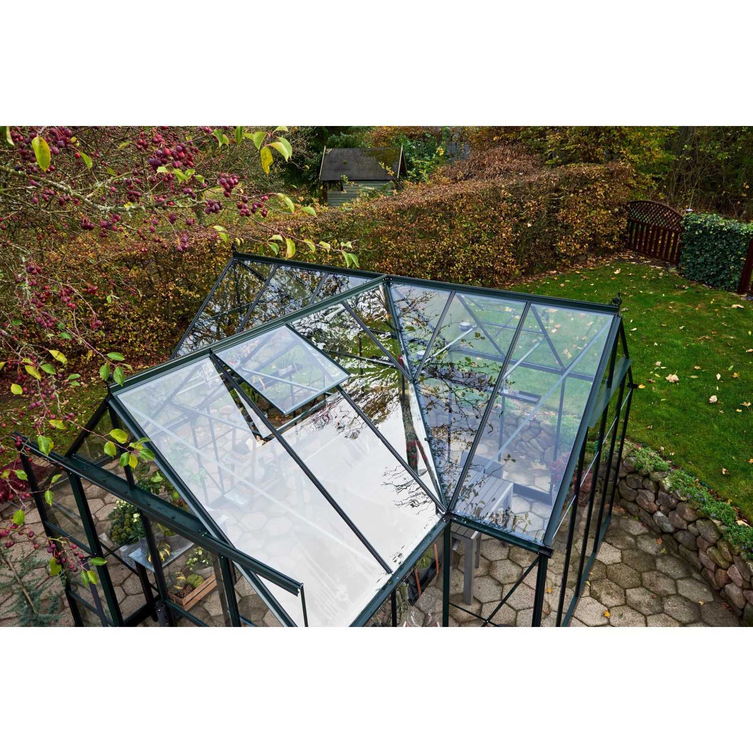 Halls Gewächshaus GardenRoom Set, grüne Rahmen, Glasdach mit geöffnetem Fenster, eingebettet in Garten.