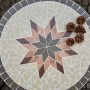 Runder, grauer Siena Garden Gartentisch Stella Ø 70 cm mit Sternmuster und Deko-Zapfen.