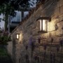 Matte, runde Philips Solar-Wandleuchte Camill an einer Steinmauer im Garten.
