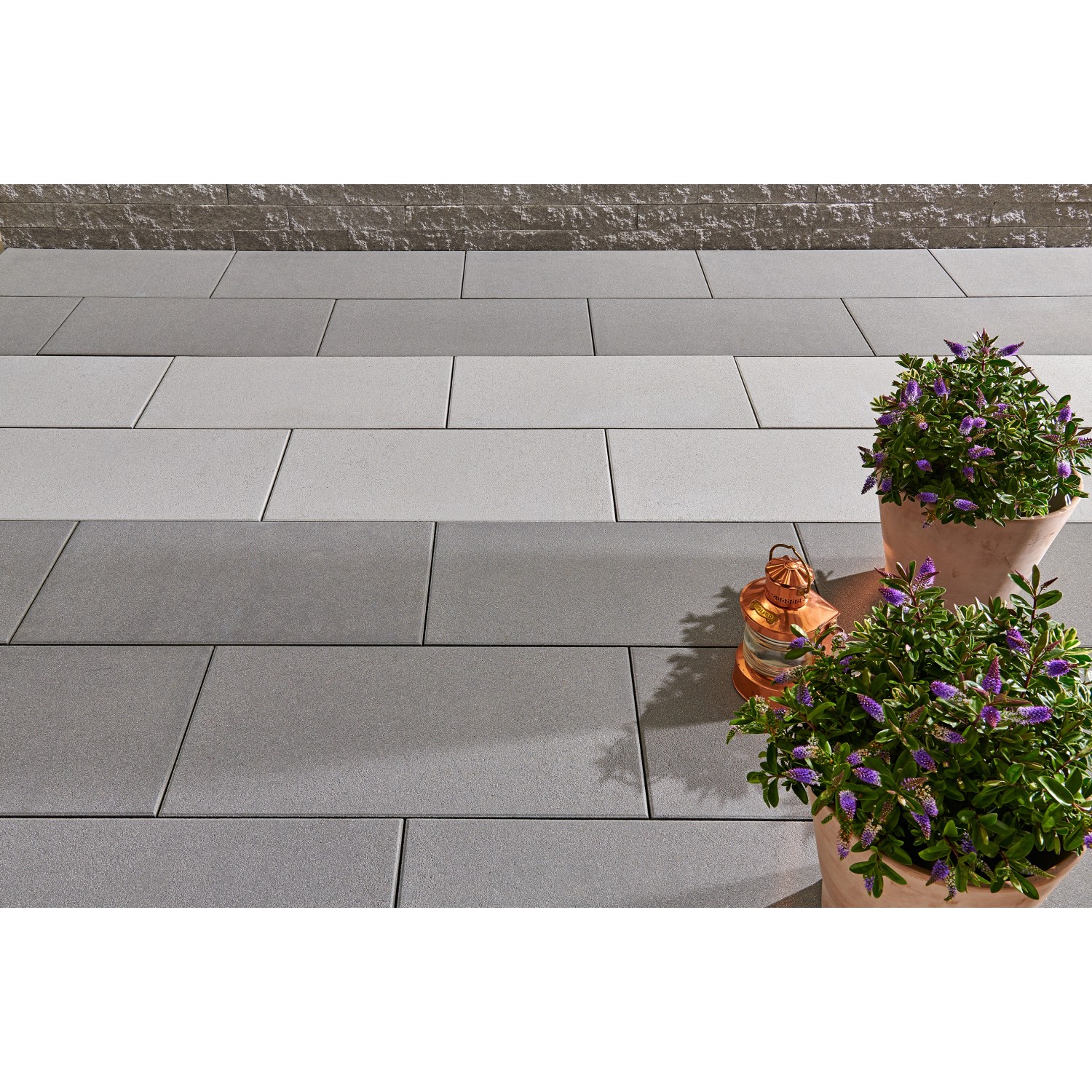 Verlegte, kugelgestrahlte, graue Kann Casavera Maxx Terrassenplatten 80x40 cm mit Pflanzen und Deko.