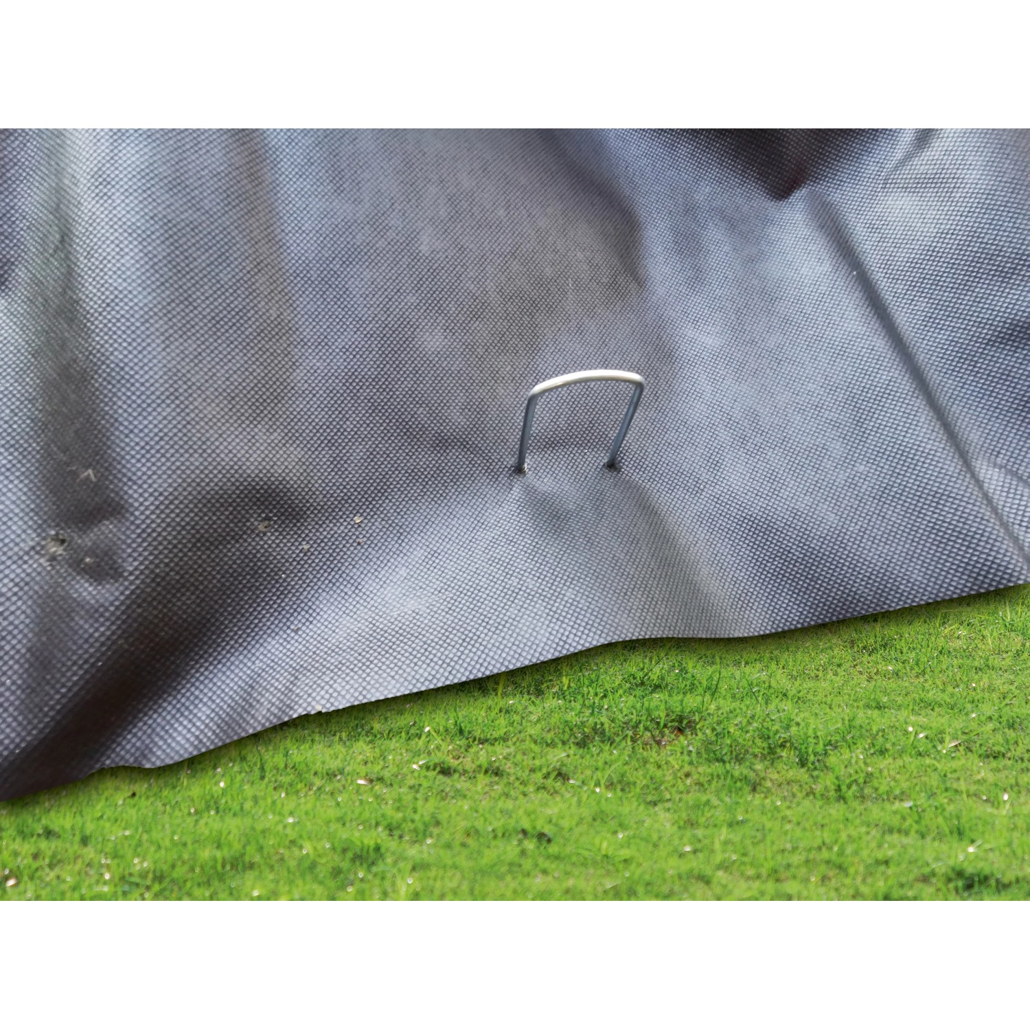 U-förmiger Folien- und Vlieshalter (14 cm) aus Stahl befestigt ein graues Vlies auf grünem Gras.