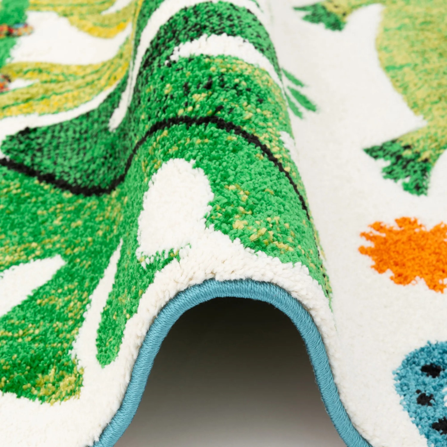 Detailansicht: Bunter Kinderteppich mit Urwald-Motiv, 120x170cm. Kurzflorteppich mit grünen Blättern und Tieren.