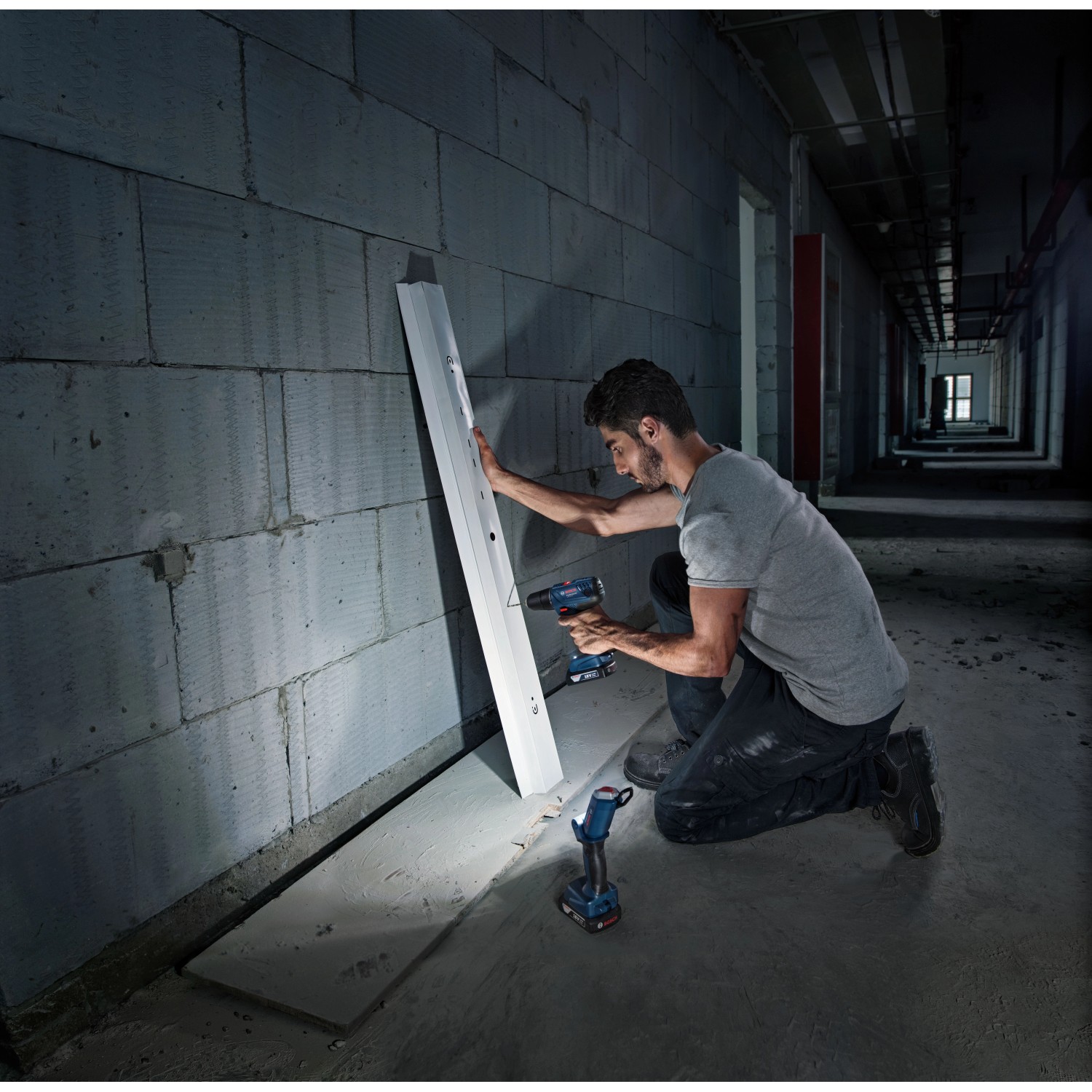 Mann schraubt mit Bosch Professional Akku-Bohrschrauber GSR 18 V-21 Solo in Wand, Akku-Lampe leuchtet.